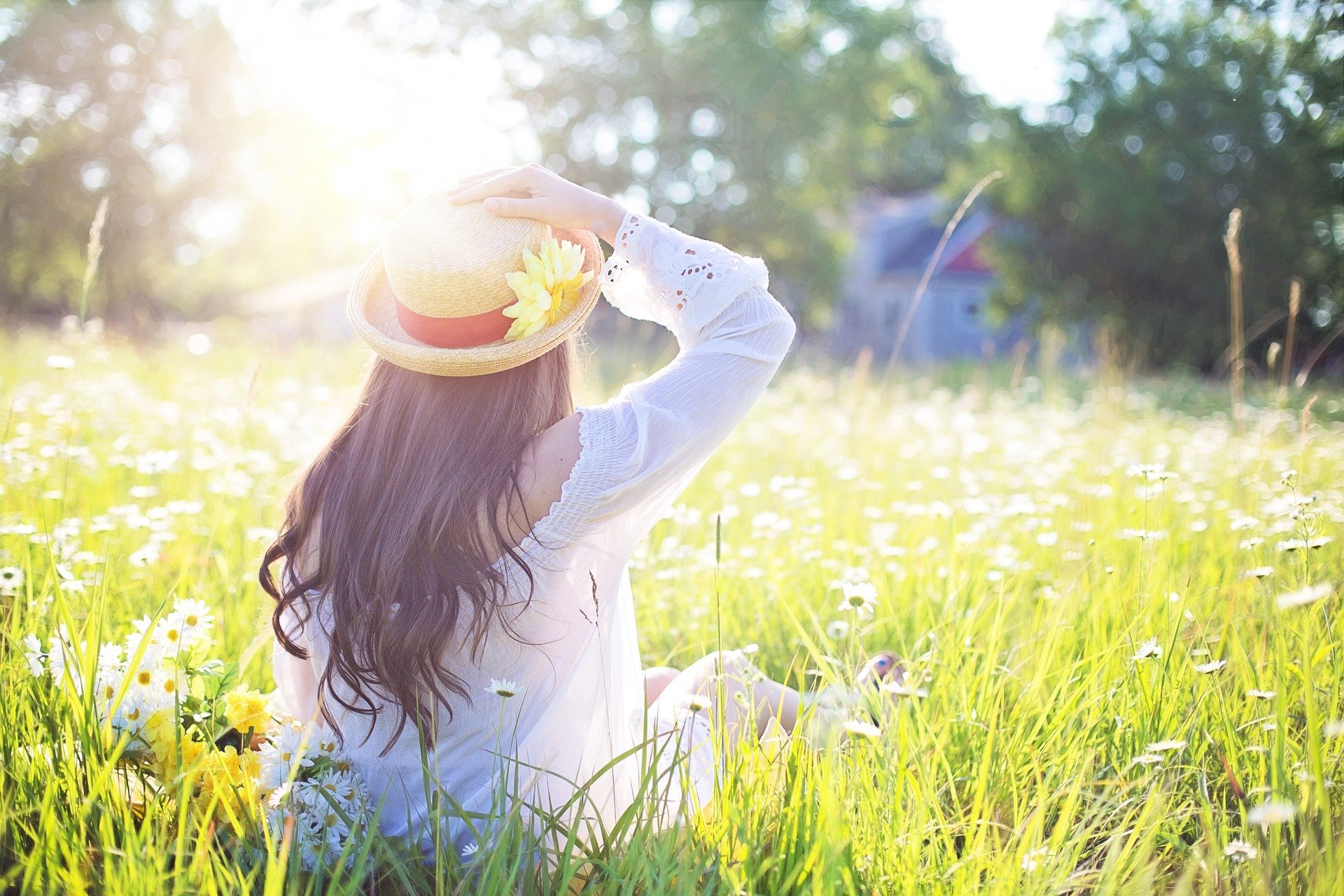 Girl in straw hat in meadow of daisies